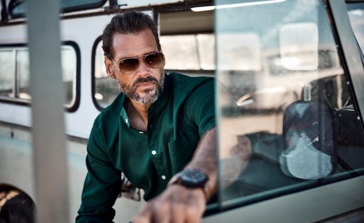 The model wears a green shirt and sunglasses