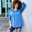 The model wears a blue long-sleeved shirt 