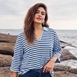 The model is wearing a sweater with orange stripes