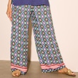 The model is wearing wide-leg trousers with a green and purple pattern