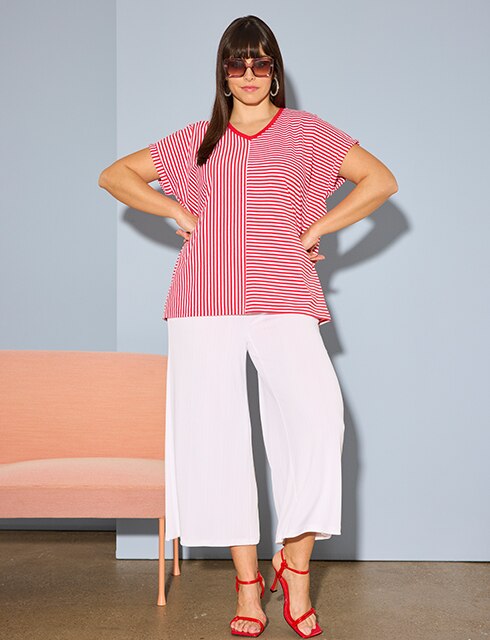 The model is wearing white trousers and a red and white striped shirt