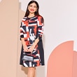 The model wears a patterned dress with the colors orange,white and black

