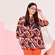 The model wearsa blouse with orange, white and dark blue lines
