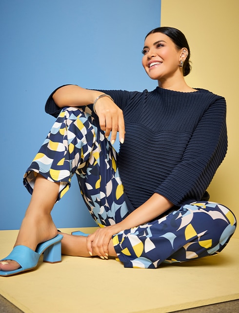 The model is wearing colorful trousers