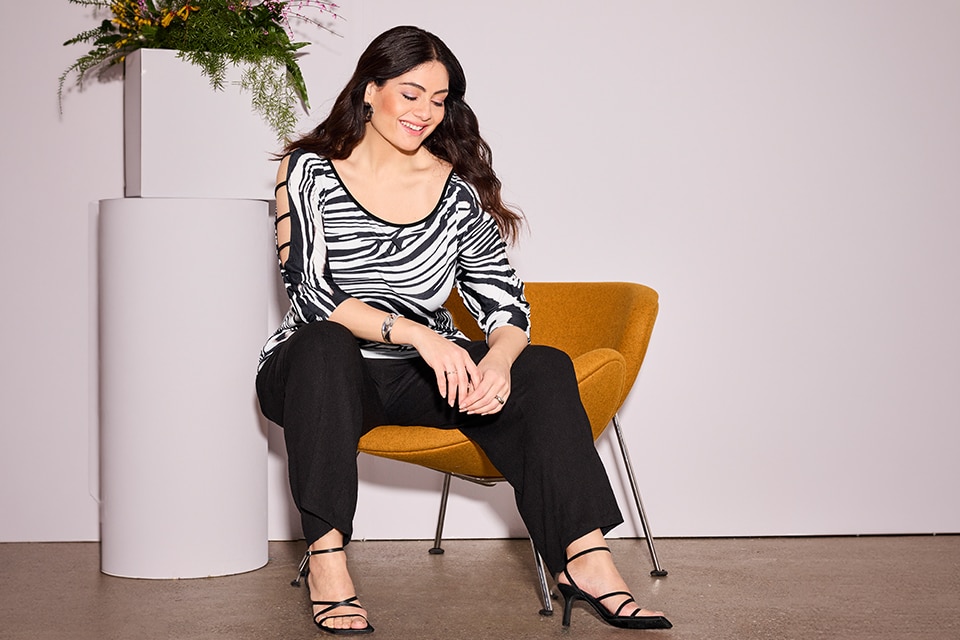 The model is wearing a black-and-white patterned shirt and black pants.