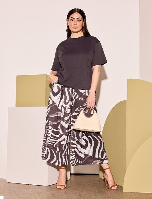 The model is wearing a brown shirt and a skirt.