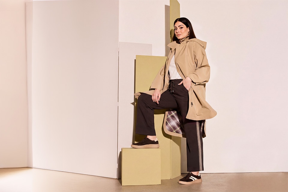 The model is wearing a beige jacket and a brown pants.