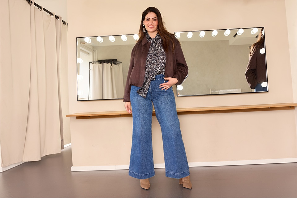 The model is wearing a brown Jacket a blouse and jeans