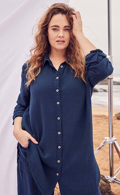 The model poses in a blue linen blouse 
