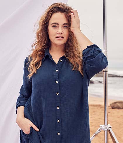 The model poses in a blue linen blouse 
