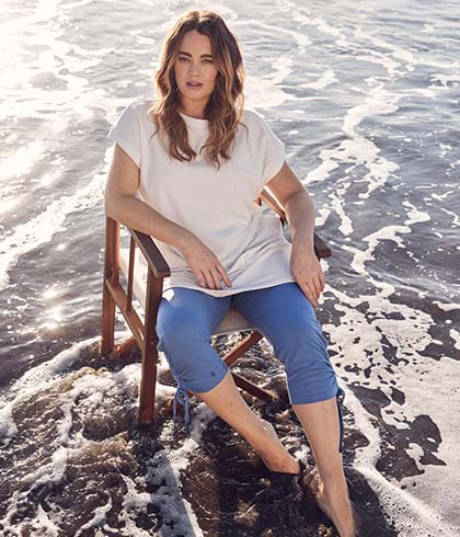 The model poses in a blouse and trousers 
