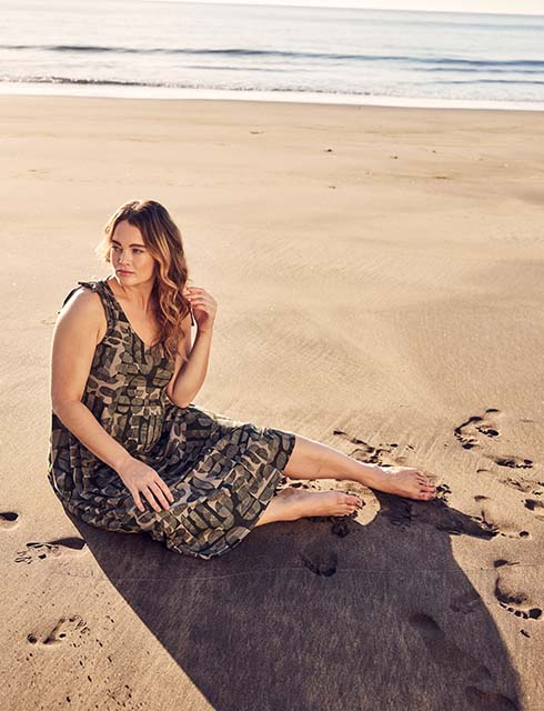 Woman posing in the sand while wearing a dress