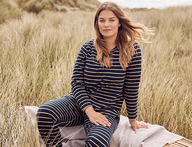 The model poses in front of the sea  while wearing pyjamas