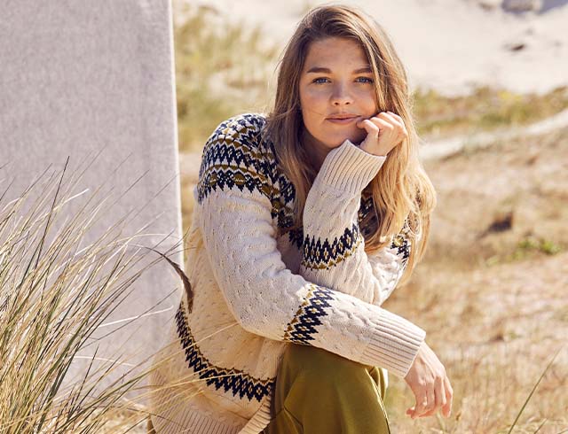 The model poses while standing on small rock near water