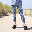 The model poses in the skinny and wears a patterned shirt with blue pants 
