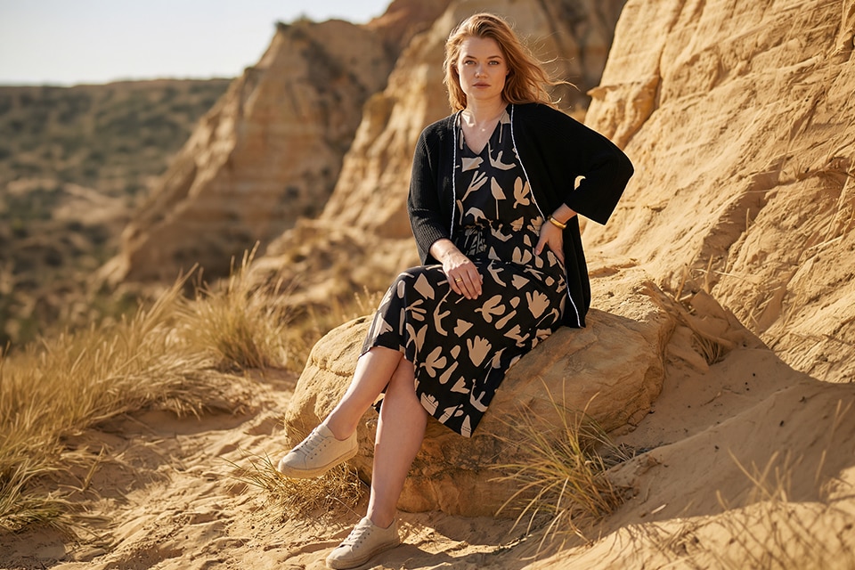 The model is wearing a black dress with a beige pattern