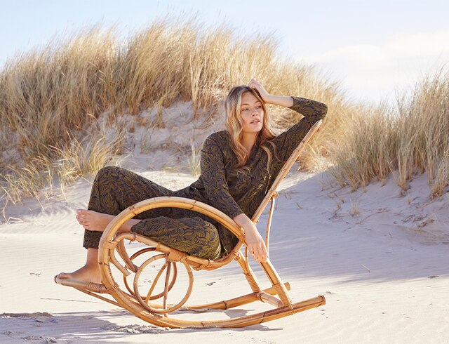 Woman in pajamas sits on a wooden chair