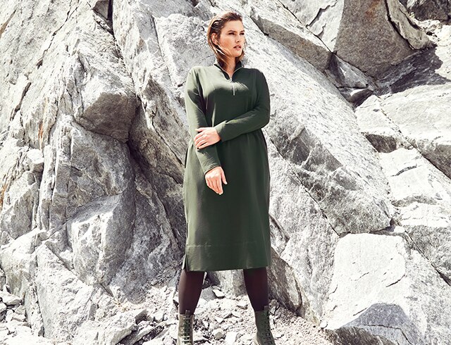 Woman in green dress standing in front of a rock face