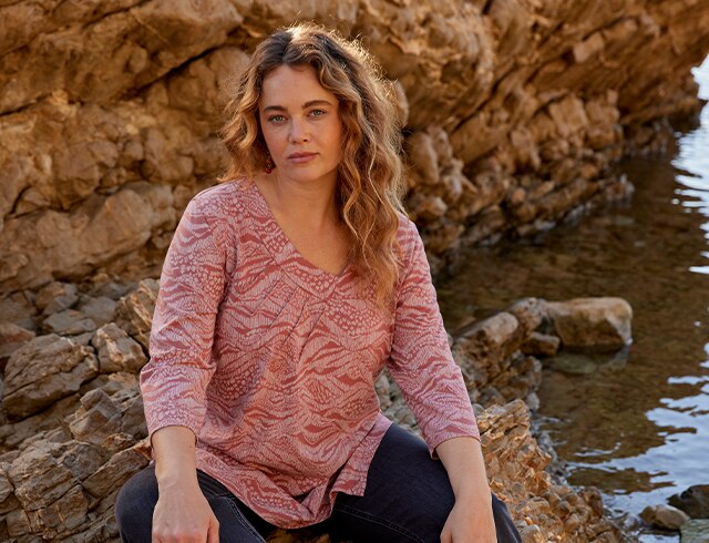 Woman in a pink T-shirt sits on some rocks