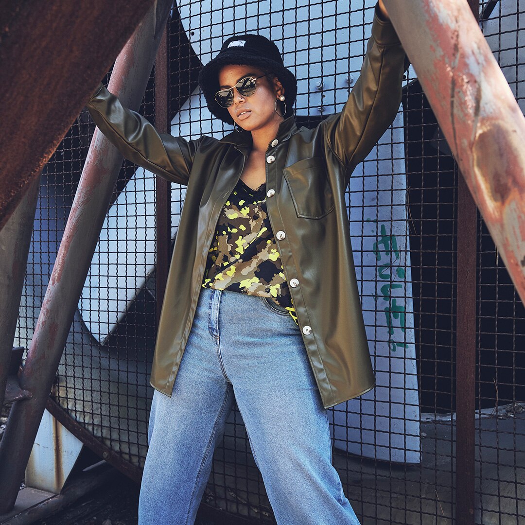 Model posing in leather shirt and hat in front of a trellis