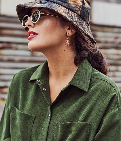 Model with sunglasses, a hat on and wearing a green blouse