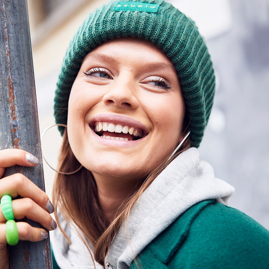 Smiling woman is wearing a green wool hat