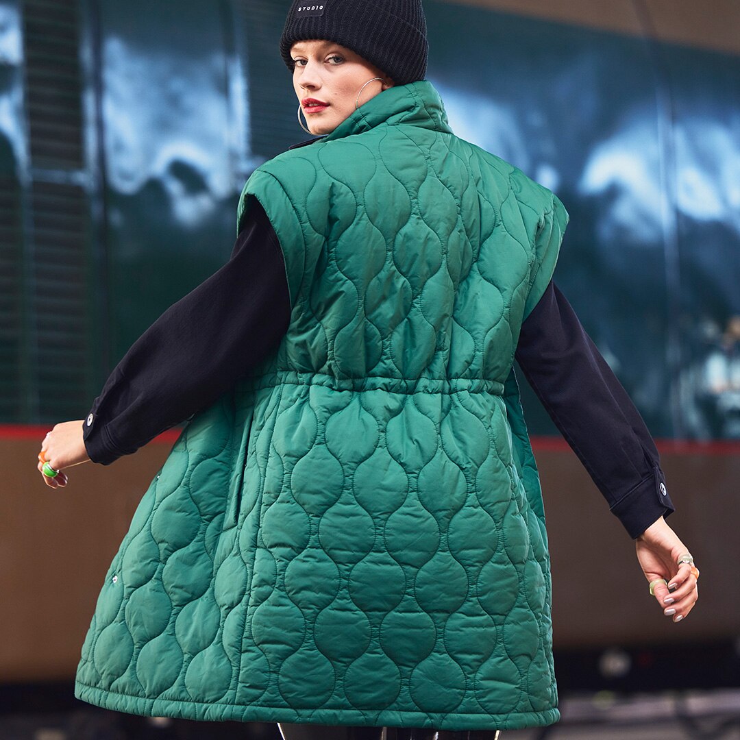 Model is posing in a green quilted vest