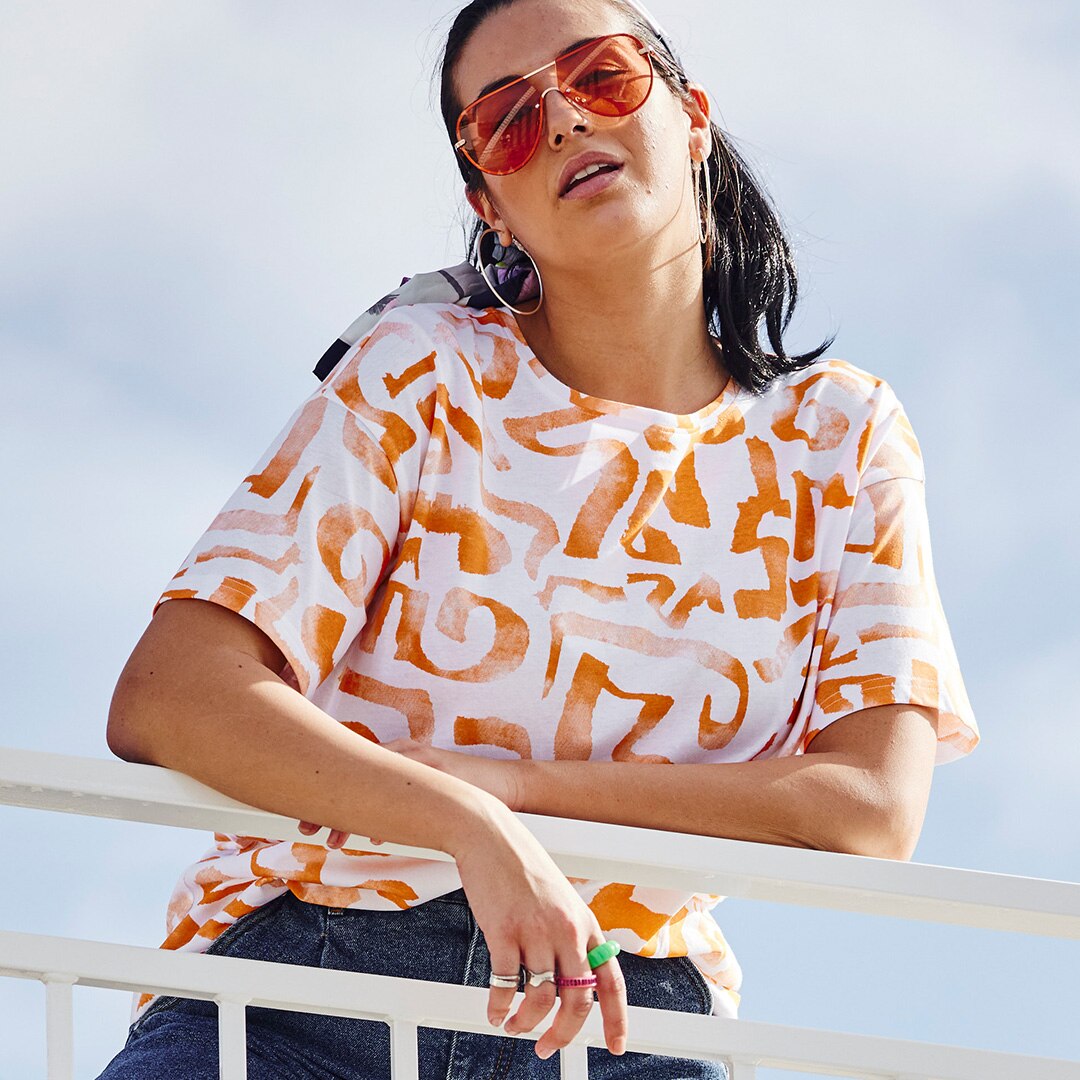 Woman wearing a white and orange t-shirt and sunglasses