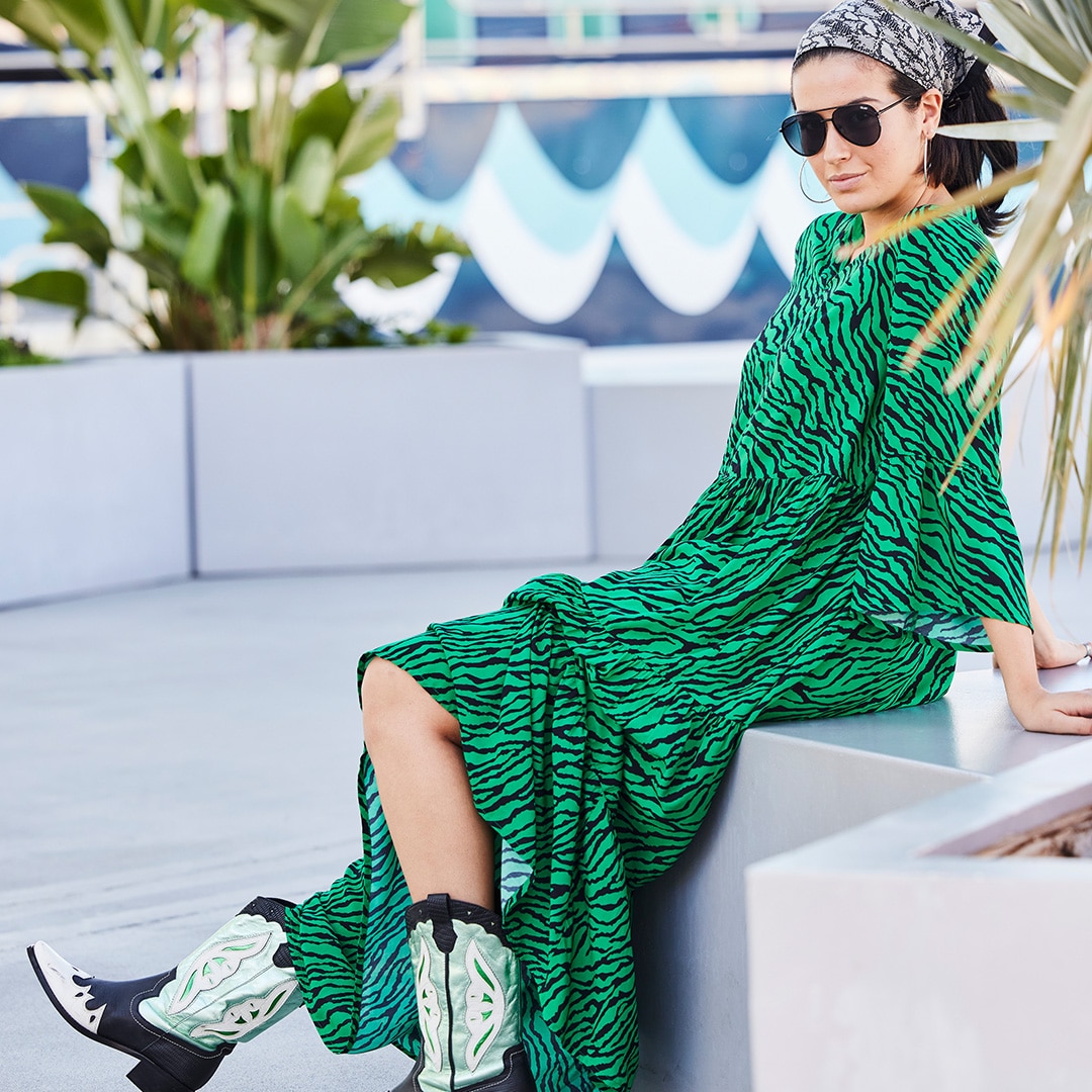 Model wearing a long green dress with animal print