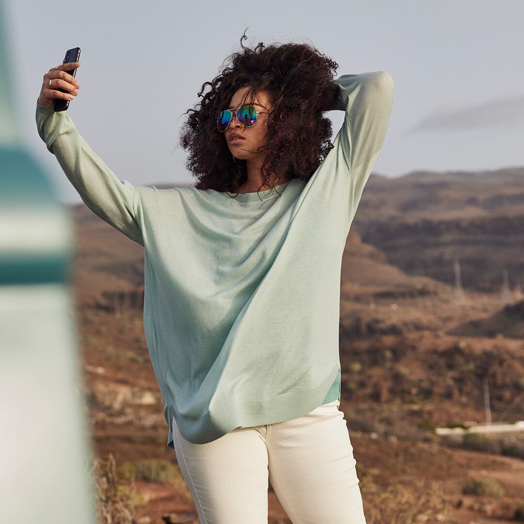Model wearing a green pullover is taking a selfie