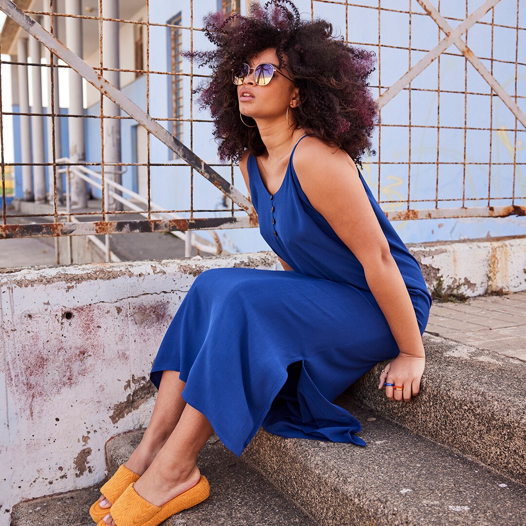 A model is sitting on the stairs and wearing a long blue dress