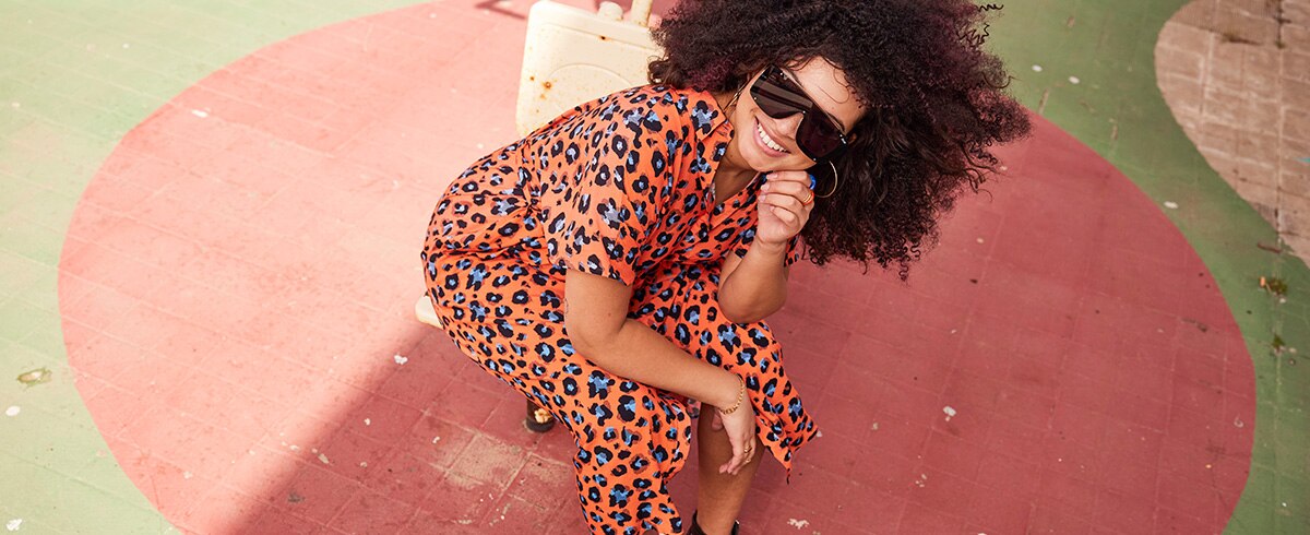 A model is wearing sunglasses and a long dress with animal print