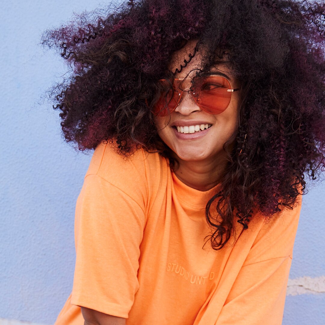A woman is smiling and wearing an orange t-shirt