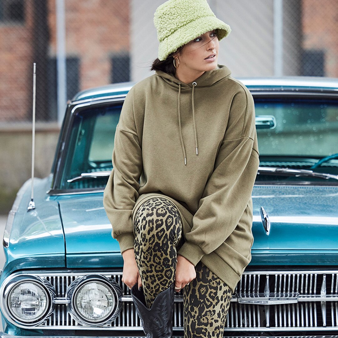 Model is wearing a long Hoodie while sitting on a car