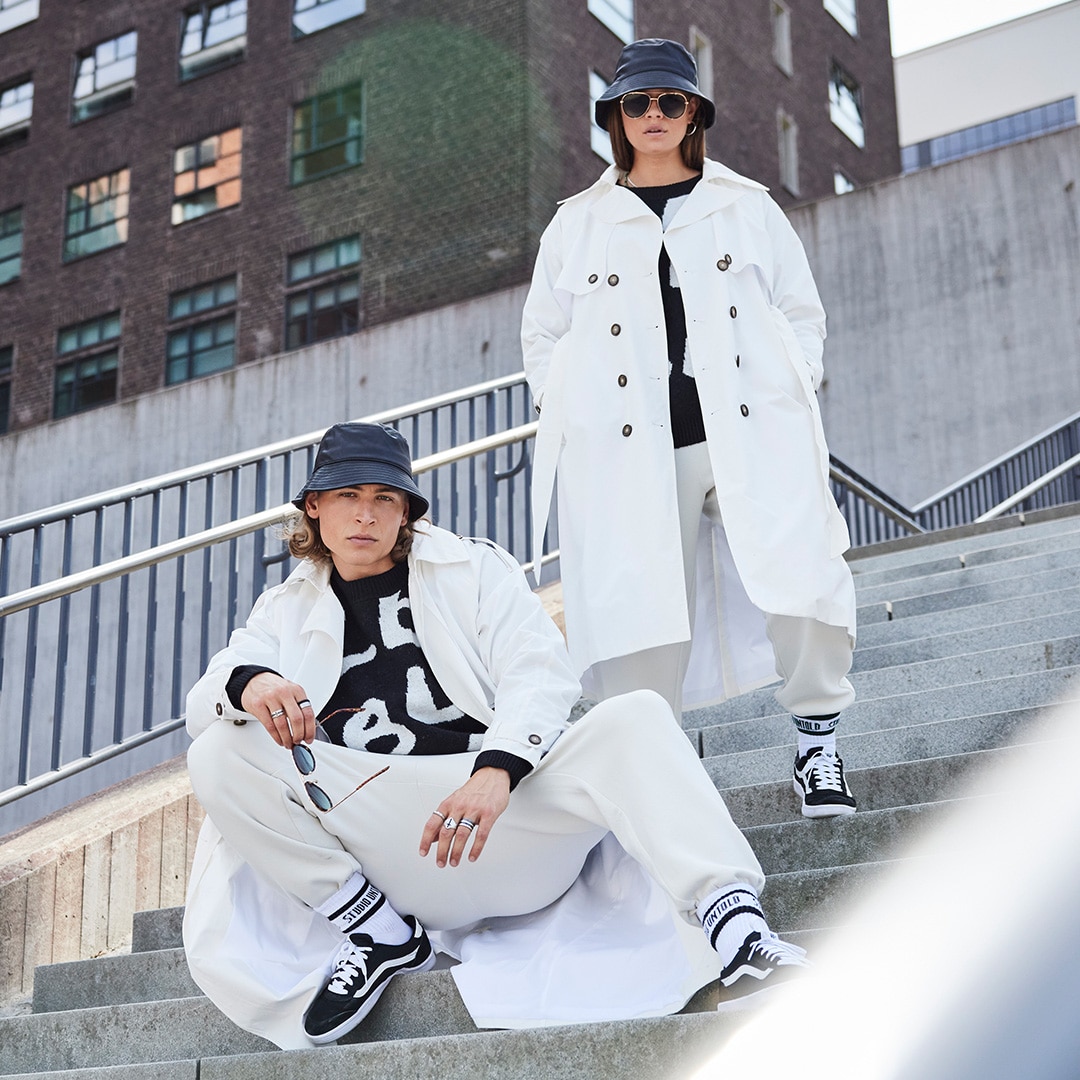 Two models wearing the same white outfit while standing on a stairway