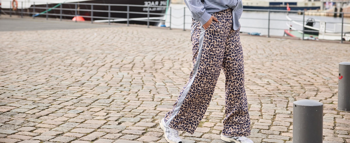 Das Model steht an einem Straßeneck und trägt ein Set aus kurzer Hose und Bluse, gestreift und mit Blüten.
