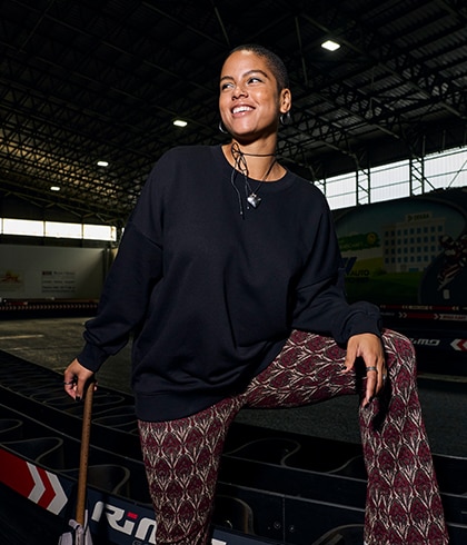 The model is wearing a black shirt and burgundy trousers with a diamond-shaped pattern.