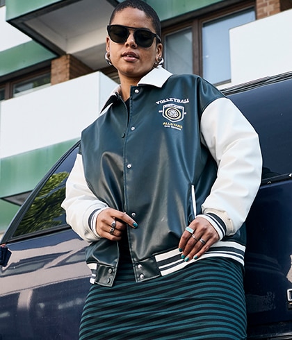 The model is wearing a black and white college jacket.