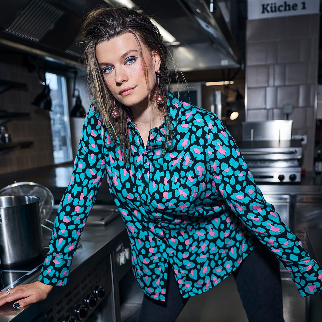 Woman is standing in the middel of a street while wearing a grey dress