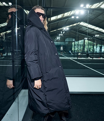 The model is wearing a black and white college jacket.