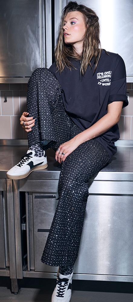 The model is wearing a burgundy knitted dress and black cowboy boots.