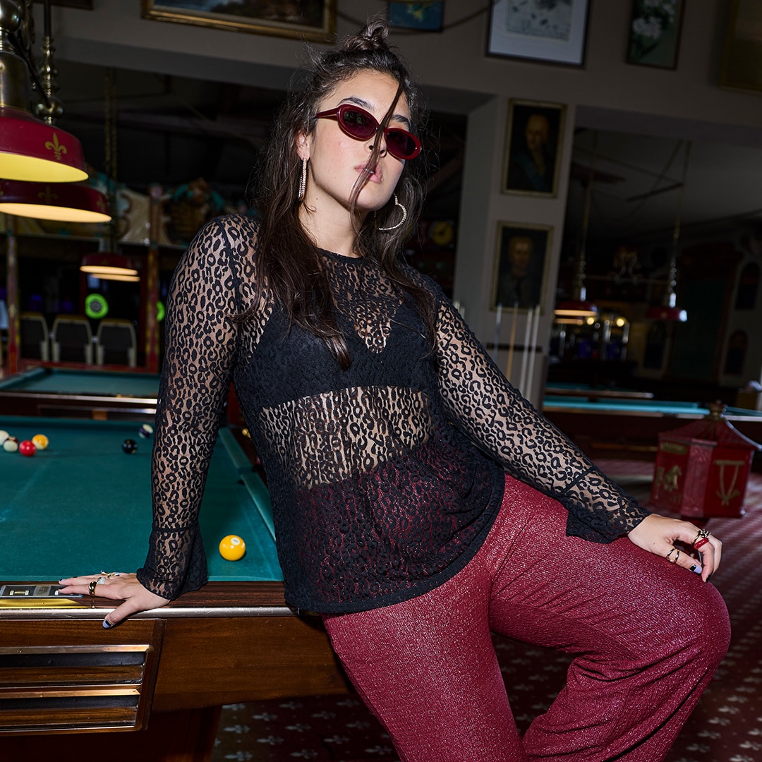 Woman is standing in the middel of a street while wearing a grey dress