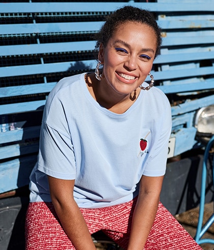 The model is wearing a black shirt and burgundy trousers with a diamond-shaped pattern.