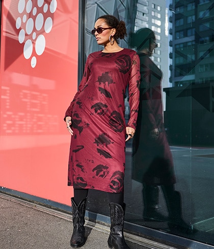 The model is wearing a black leather jacket over a purple jumper.