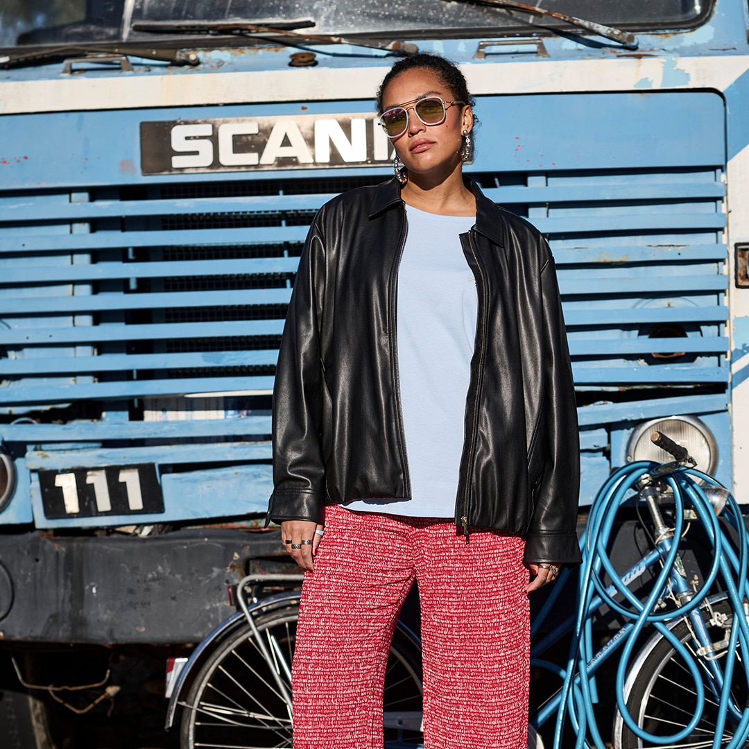 The model is wearing a purple sweater and a short black patterned skirt.