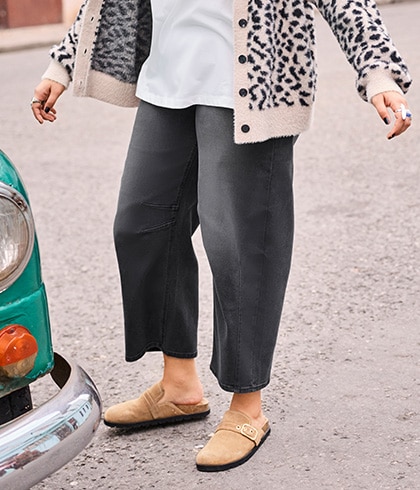 The model is wearing a black leather jacket over a purple jumper.