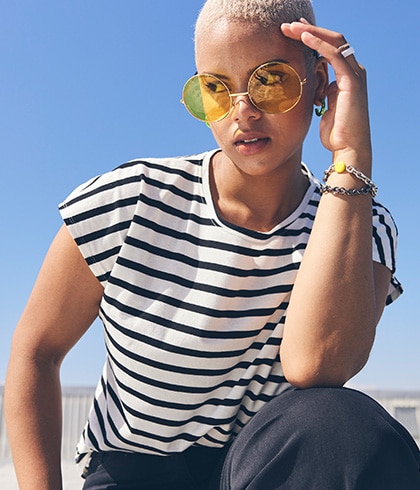 Woman with short hair, sunglasses and a striped shirt.