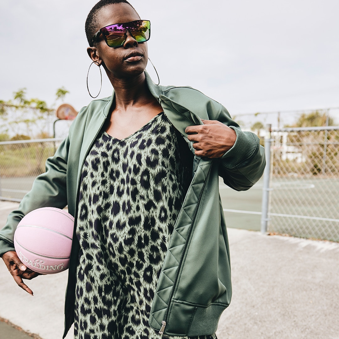 Dark-skinned model with a green dress with animal print and a green bomber jacket