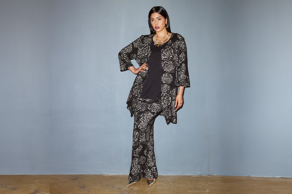 The model poses in the studio and wears a blue and white striped blouse with an additional floral print with her jeans