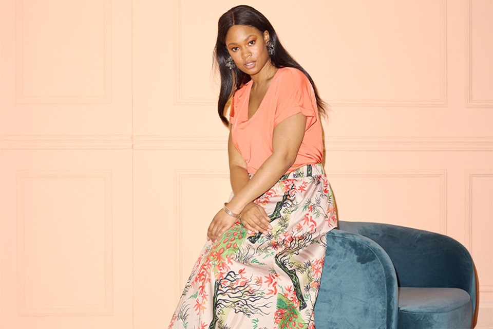 The model wears a floral skirt